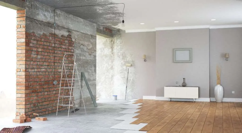 Stue under renovering med fritlagt murpille og nyt trægulv